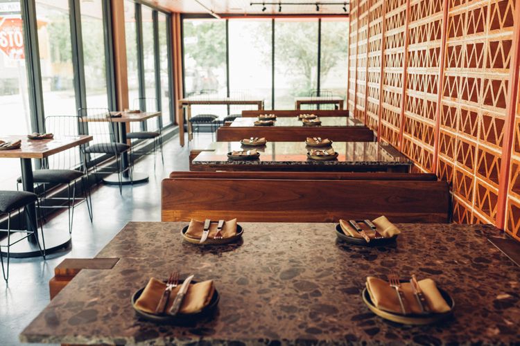 Dining tables set in a restaurant with wooden accents and large windows