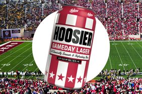 A can of Hoosier Gameday Lager with a football stadium in the background prominently featuring Indiana Universitys emblem