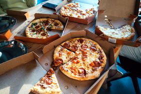 Assorted pizzas in open delivery boxes on a table
