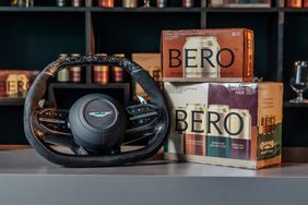 An Aston Martin steering wheel displayed next to boxed beverage packages labeled BERO on a countertop