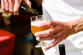 Person pouring beer into a glass with a foamy top