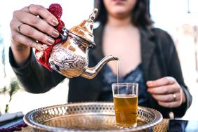 A person pouring Moroccan mint tea into a glass. 