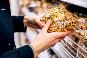Person holding a bag of pretzels in a grocery store aisle