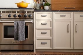 Silver hardware installed on kitchen cabinets next to a stove