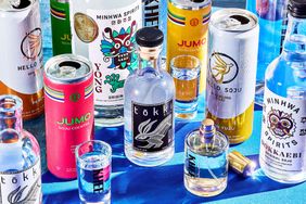 A selection of soju bottles and cans including brands like Tokki Minhwa Spirits Jumo and Hello Soju arranged on a blue surface