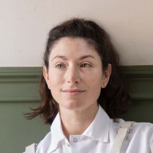 A person glancing sideways wearing a white shirt seated indoors