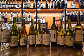 A selection of wine bottles displayed on a counter in front of shelves of wine bottles
