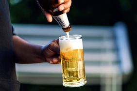 A person pouring beer into a glass with foam forming at the top