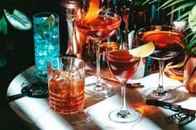A selection of cocktails displayed on a table featuring various glasses with different garnishes and surroundings indicative of a bar scene
