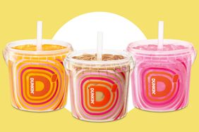 Three Dunkin beverage cups with colorful designs each containing an iced drink and a straw