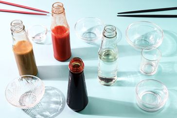 Assorted bottles of sauces and condiments with small serving dishes on a surface