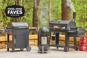 three charcoal smokers on an outside deck