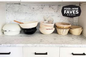 Countertop with breadproofing baskets and bowls arranged below a marble backsplash