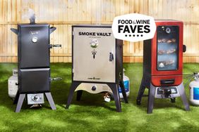 Three gas smokers propped outside on a patch of grass.