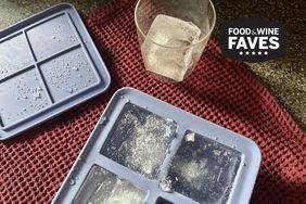 Ice cube trays and a glass with an ice cube on a textured cloth surface
