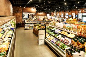 A grocery store with produce and packaged goods on display in aisles shelves and lighting create an organized shopping environment