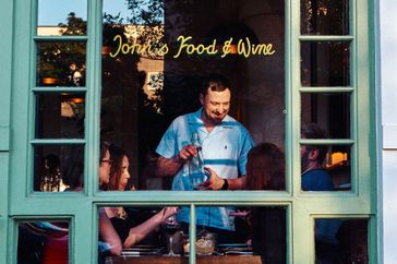A server at a table of diners as seen through a restaurant window at John's Food & Wine.