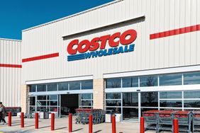 Exterior view of a Costco Wholesale storefront with shopping carts and parking area at the entrance