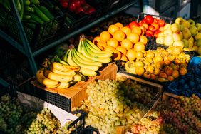 A display of various fruits including bananas oranges apples and grapes in baskets and crates