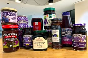 A selection of various grape jellies and preserves displayed on a wooden surface