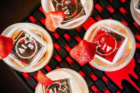 Cocktail glasses with decorative ice cubes and strawberry garnishes on a tray