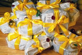 Wrapped cakes with labels and yellow ribbons arranged in a festive presentation with decorative ornaments