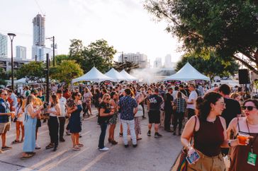 A group of people gathered outdoors at an event with tents at at Hot Luck Festival.