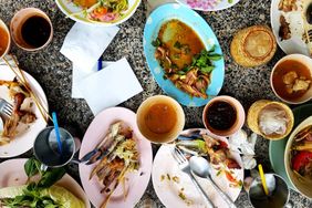 Plates of leftover food and drinks on a table at a restaurant