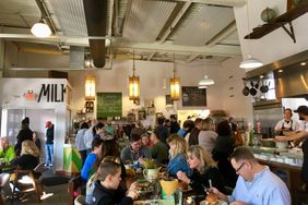 A busy brunch restaurant with diners seated at tables and staff visible in the background