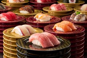 Plates of sushi stacked on a table showcasing various nigiri pieces at Sushiro.