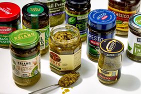 Various jars of pesto sauce displayed with a spoon showcasing brands like Raos Priano and Classico