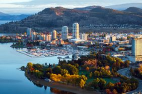 Aerial view of Kelowna downtown with lakefront buildings marina and surrounding hills