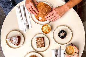 A table with various pastries, coffee, and two people seated