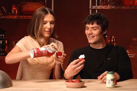 Millie Bobbie Brown and Louis Partridge tasting whipped cream and strawberries.