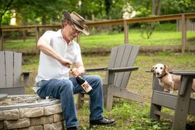 Erik Martella opening a bottle of wine with his dog, Red.