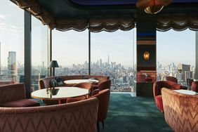 Upscale rooftop bar with a skyline view of Manhattan featuring glass walls and comfortable seating