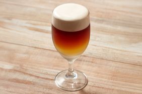 A glass of a layered brunch drink on a wooden surface