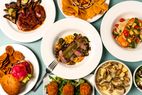 Various plated dishes including roasted meat seafood salad and appetizers arranged on a table