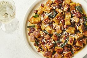 Plate of ricotta gnocchi with toppings and a glass of drink nearby
