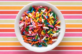 Bowl of colorful sprinkles on a striped background