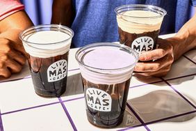 Three Taco Bell cold foam drinks on a tiled table being held by hands