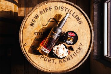 A bottle of New Riff Distilling bourbon with ice cream on a wooden barrel