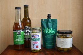 Selection of olive brines and cocktail ingredients displayed on a wooden surface