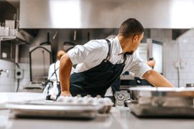 A chef in a kitchen reaching for something
