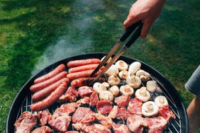 Grilled sausages steak and mushrooms on a barbecue grill outdoors