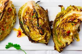 Grilled cabbage wedges garnished with herbs and a spicy dressing