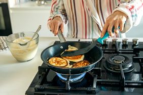 Person cooking pancakes on a nonstick pan over a gas stove