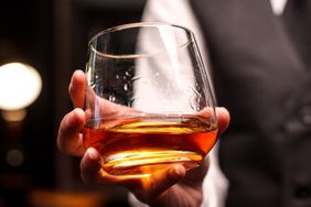A person holding a glass of bourbon