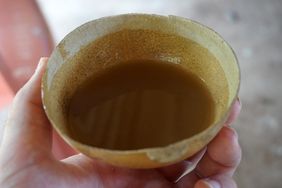 A hand holding a cup with a yellowish liquid likely honey liqueur